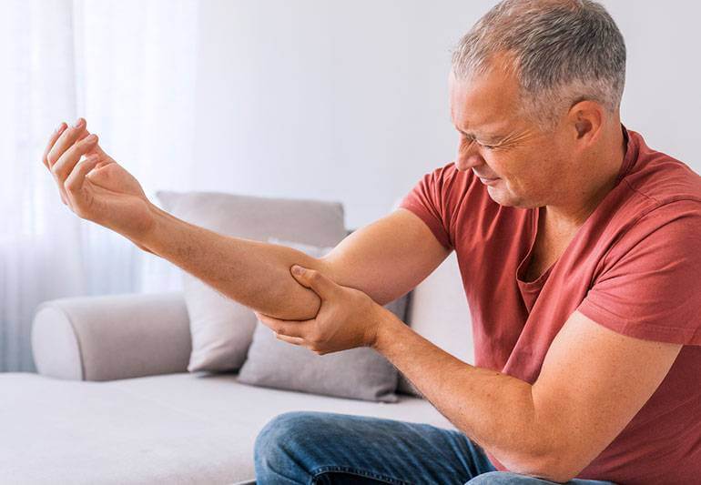 Man holding his elbow because of elbow pain
