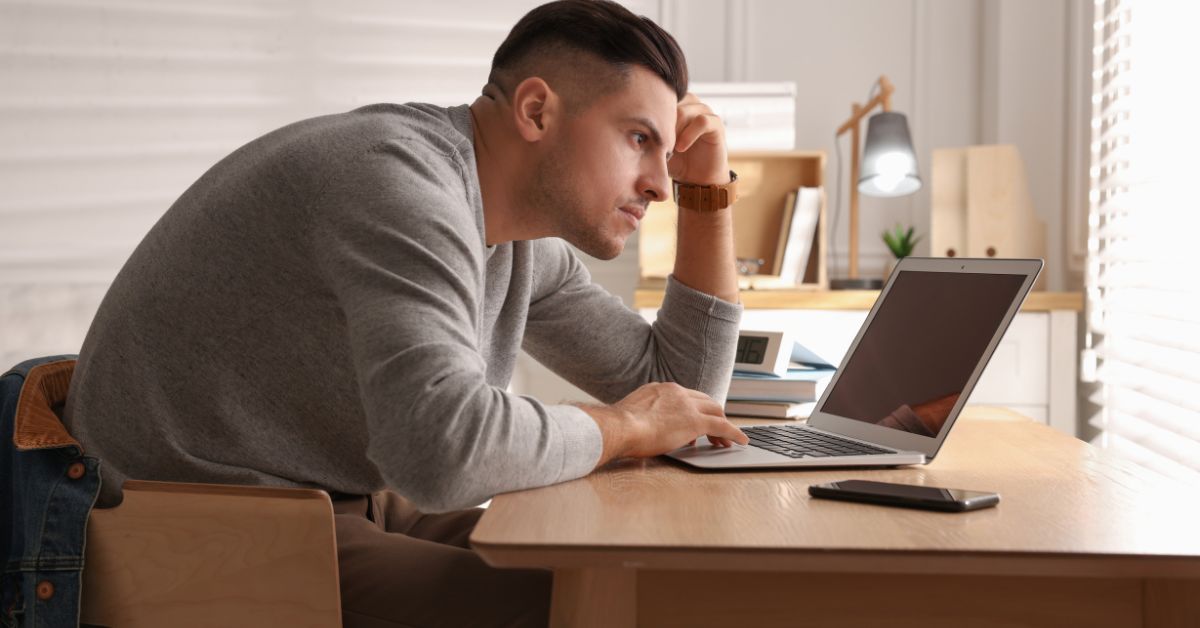 Man hunched over laptop with poor posture causing shoulder pain